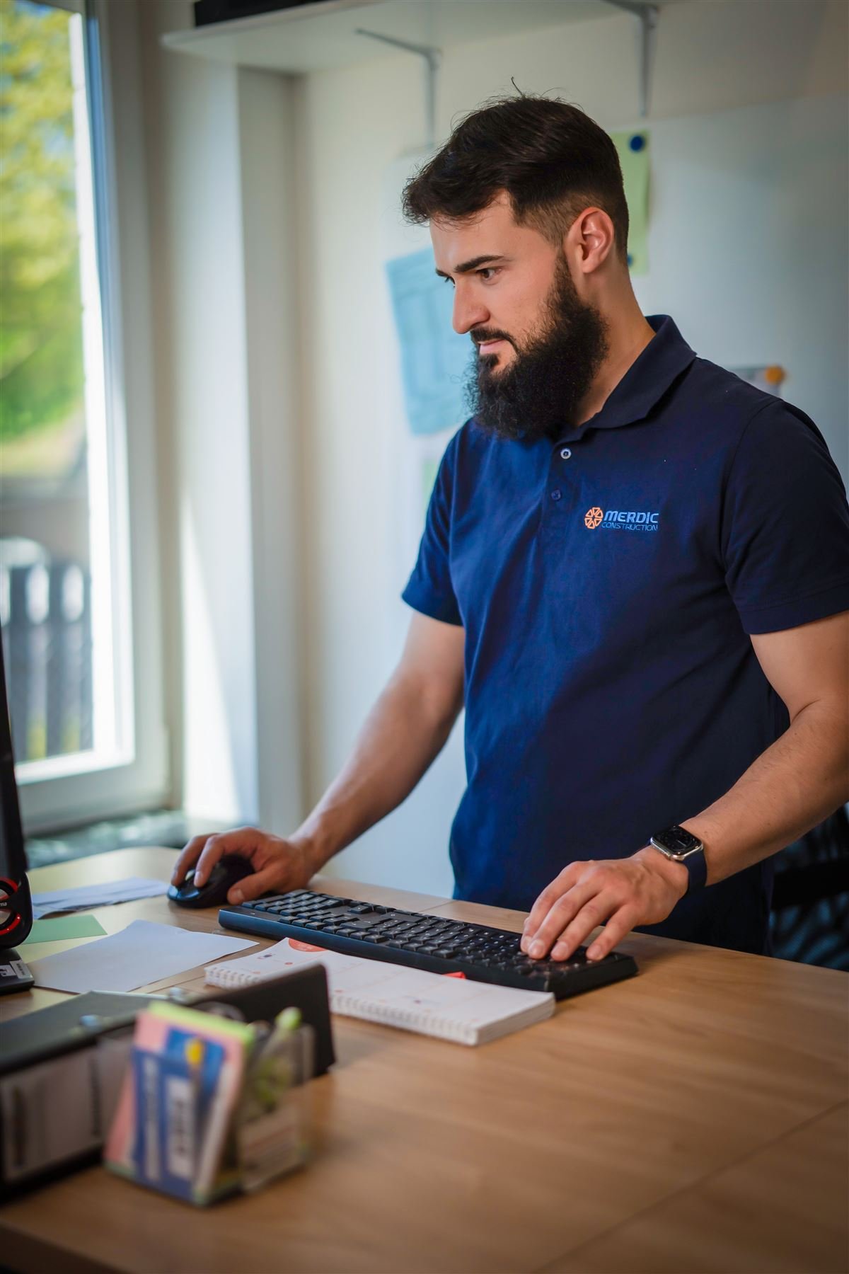 Harun Merdic bearbeitet Kundenanfragen im Büro von Merdic Construction